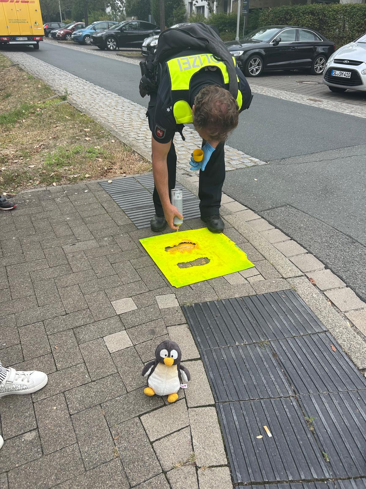 Ein Polizist markiert gelbe Fußspuren auf dem Gehweg